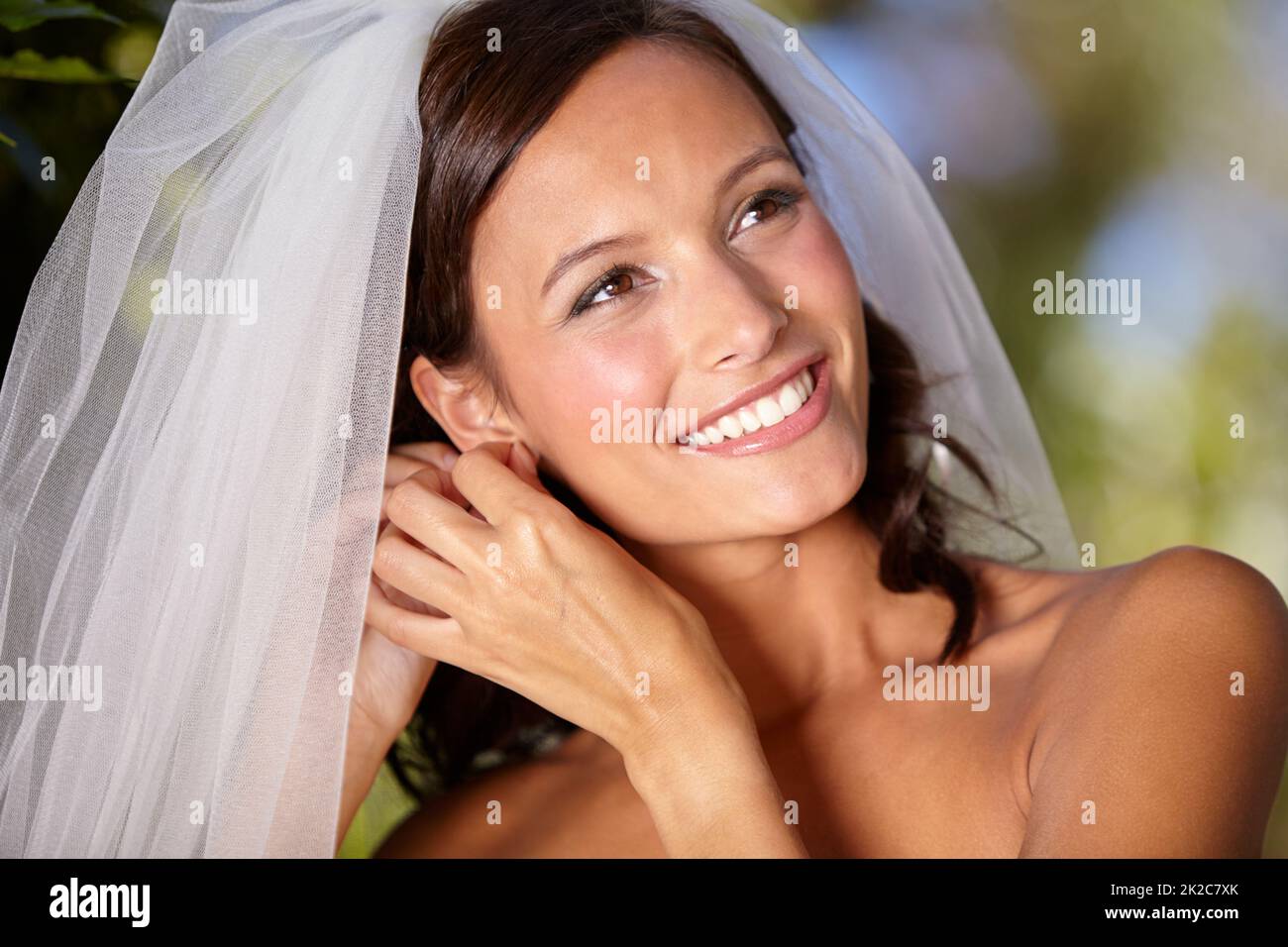 Die kleinen Details zu beheben. Schöne Braut, die ihre Ohrringe an ihrem Hochzeitstag anpasst. Stockfoto