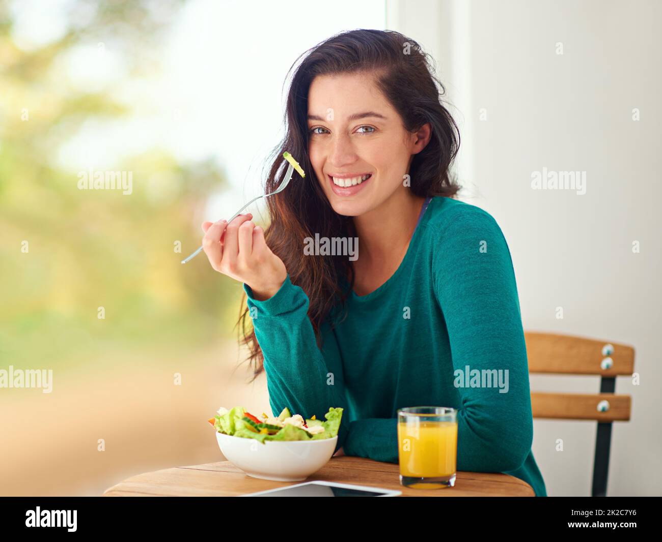 Gesundheit ist Glück. Porträt einer jungen Frau, die zu Hause einen gesunden Salat isst. Stockfoto