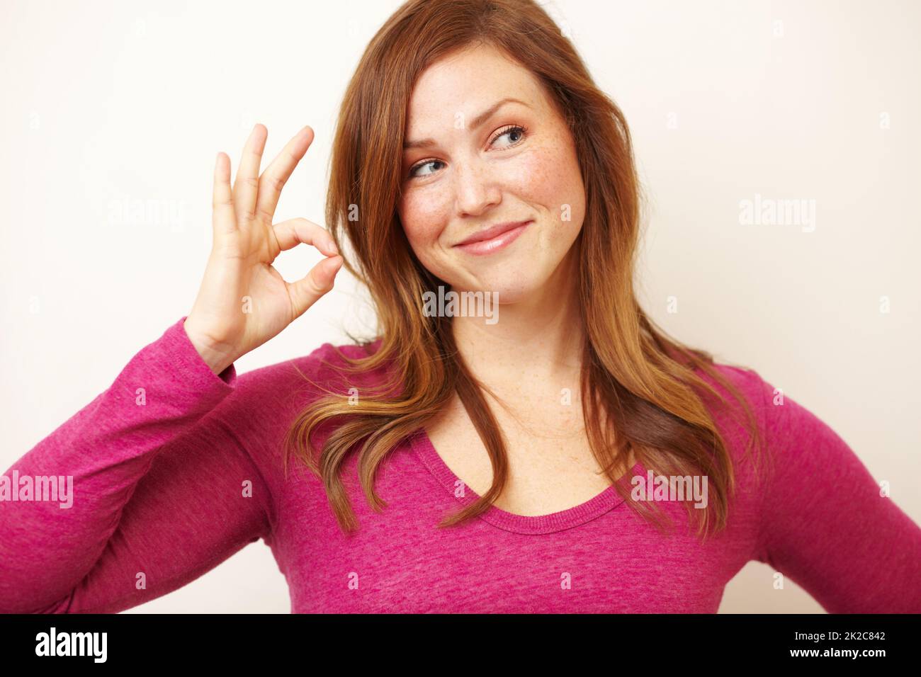 Alles ist A-OK. Ausgeschnittene Aufnahme einer schönen jungen Frau, die lächelt, während sie ein OK-Schild zeigt. Stockfoto