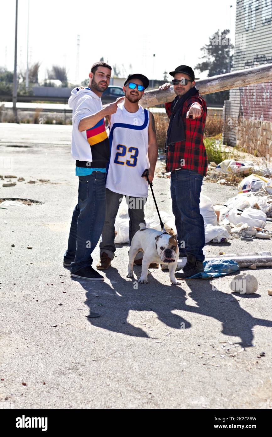Das Leben auf der Straße. Drei männliche Männer in einer schlechten Nachbarschaft mit ihrem Hund. Stockfoto