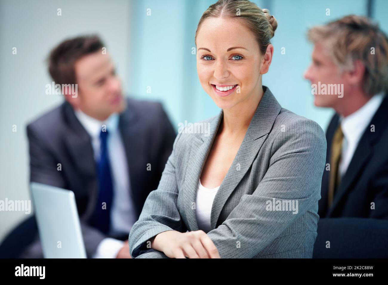 Lächelnde Führungskraft mit Geschäftsleuten. Porträt einer schönen Führungskraft mit einem Lächeln und Geschäftsleuten im Hintergrund. Stockfoto