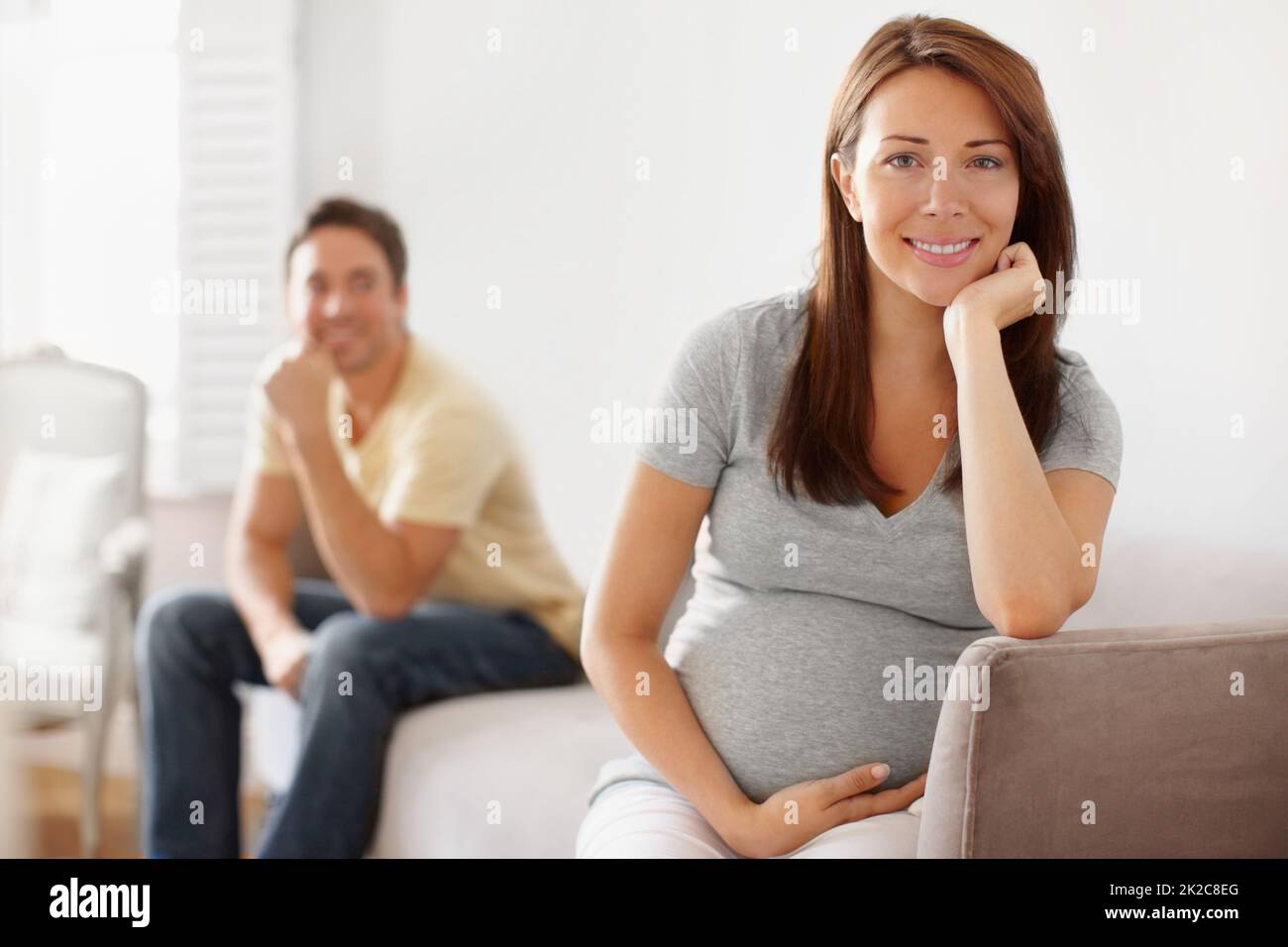 Sie will ein Mädchen und er will einen Jungen. Porträt einer hübschen jungen Schwangeren mit ihrem Ehepartner im Hintergrund. Stockfoto