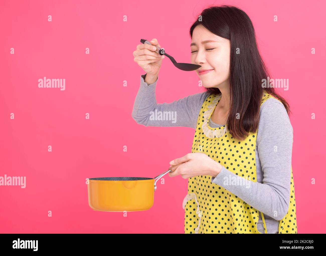 Junge Frau Hausfrau trägt Küchenschürze beim Kochen Stockfoto