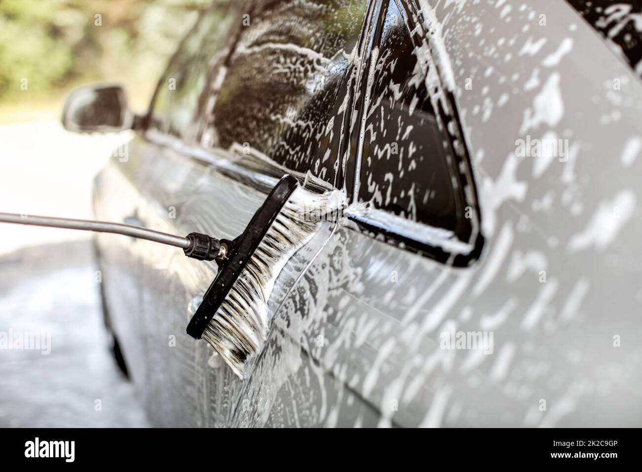 Seite von Silver Auto in Self-Service-Autowaschanlage gewaschen, Pinsel, Anschläge in Shampoo und Schaum. Stockfoto