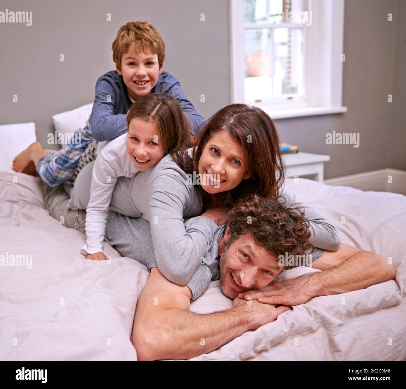 Zeit mit der Familie. Aufnahme einer glücklichen vierköpfigen Familie im Schlafzimmer. Stockfoto