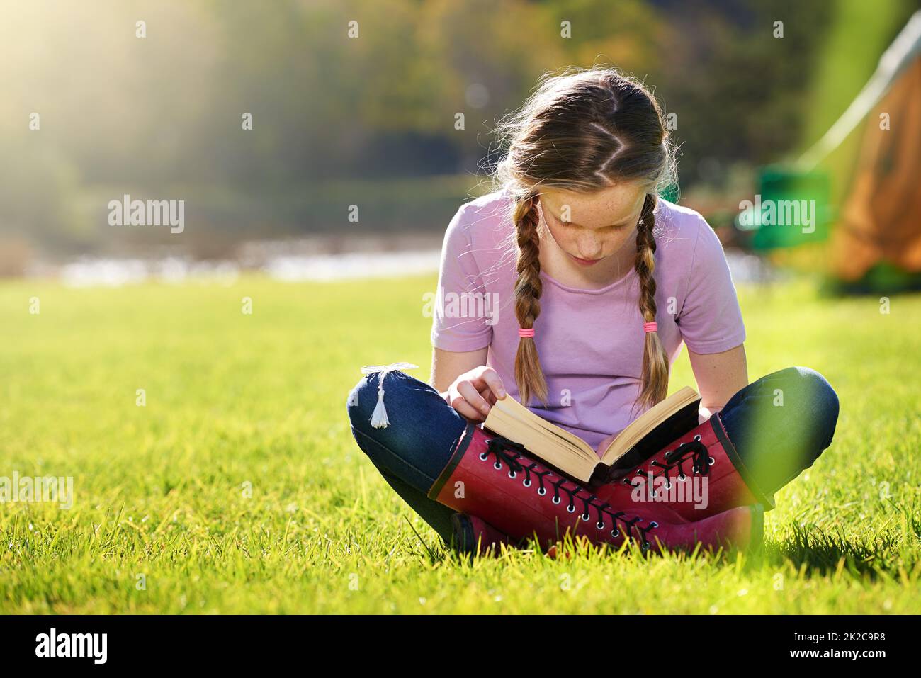 Lernen Sie den ganzen Sommer lang weiter. Aufnahme eines Teenagers, das sich mit einem Buch auf dem Rasen entspannt. Stockfoto