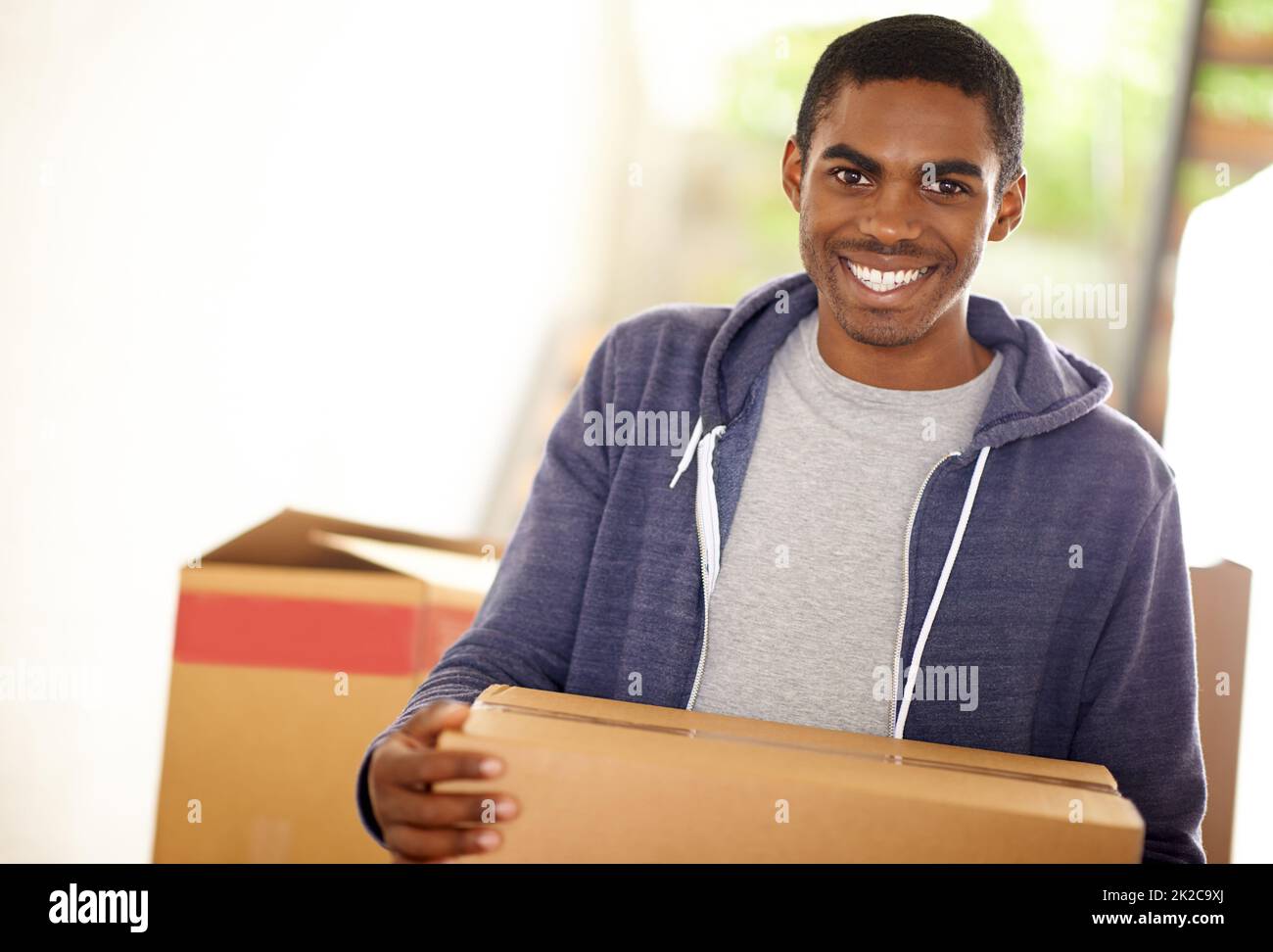 HES Umzug. Ein hübscher junger Mann, der Kisten verpackt. Stockfoto