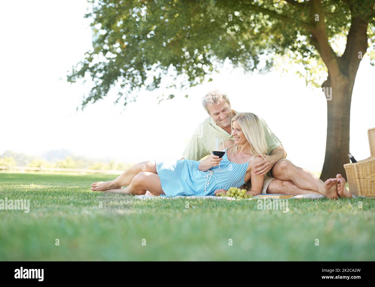 Nicht einmal die Aussicht ist mit Ihrer Schönheit vergleichbar. Ein lächelnder Ehemann und eine lächelnde Frau genießen ein gemütliches Picknick im Park. Stockfoto