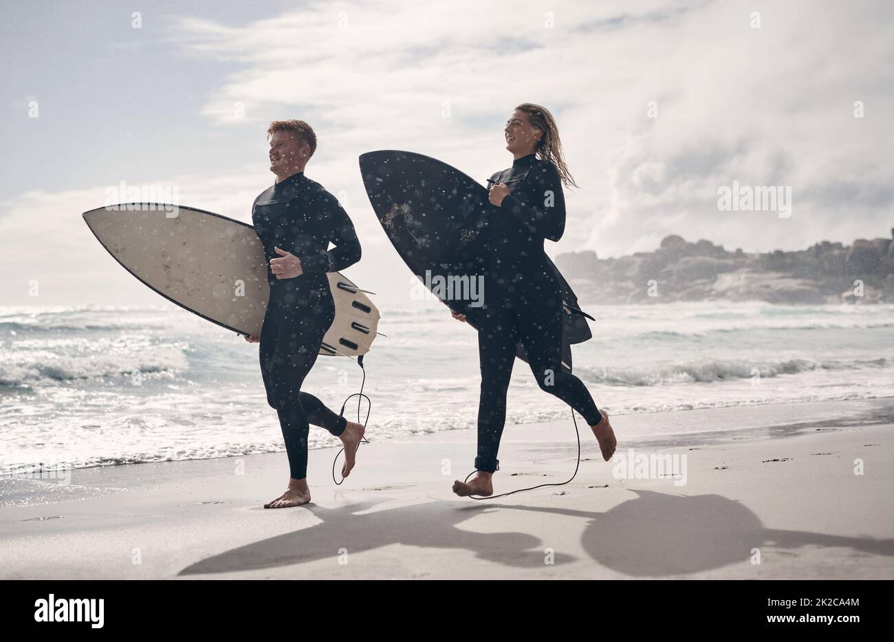 Waren süchtig nach dem Ansturm. Aufnahme eines jungen Paares, das gemeinsam am Strand surft. Stockfoto