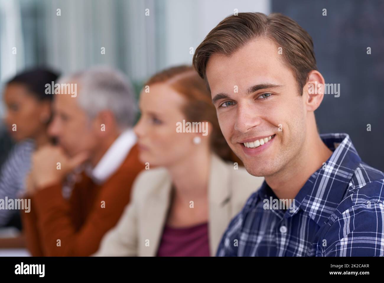 HES hat seinen Platz im Unternehmen gefunden. Ein junger Geschäftsmann, der während eines Arbeitsmeeting lächelt. Stockfoto