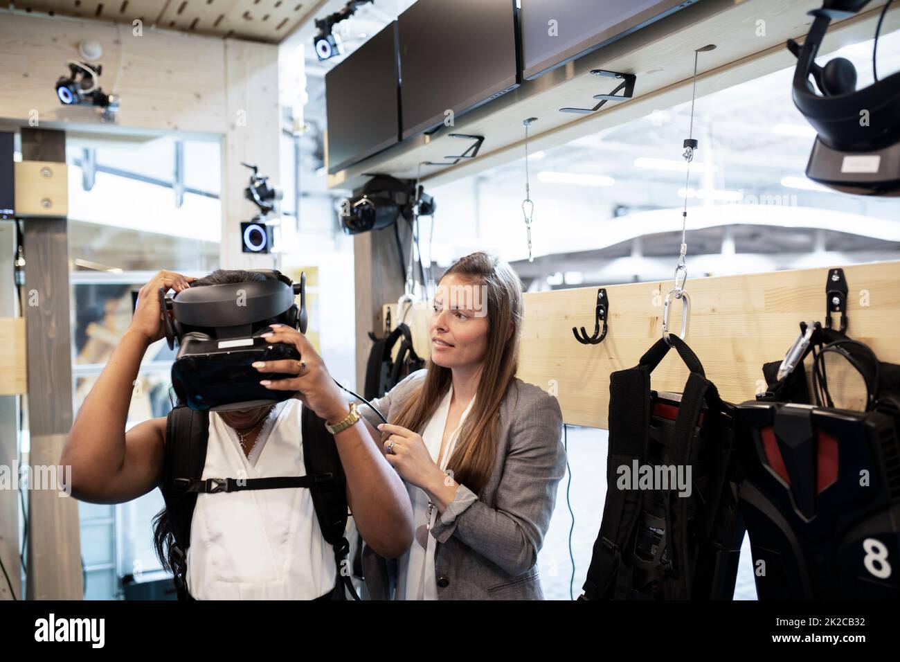 Frau, die Kollegen mit Kopfbedeckungen für virtuelle Realität unterstützt Stockfoto