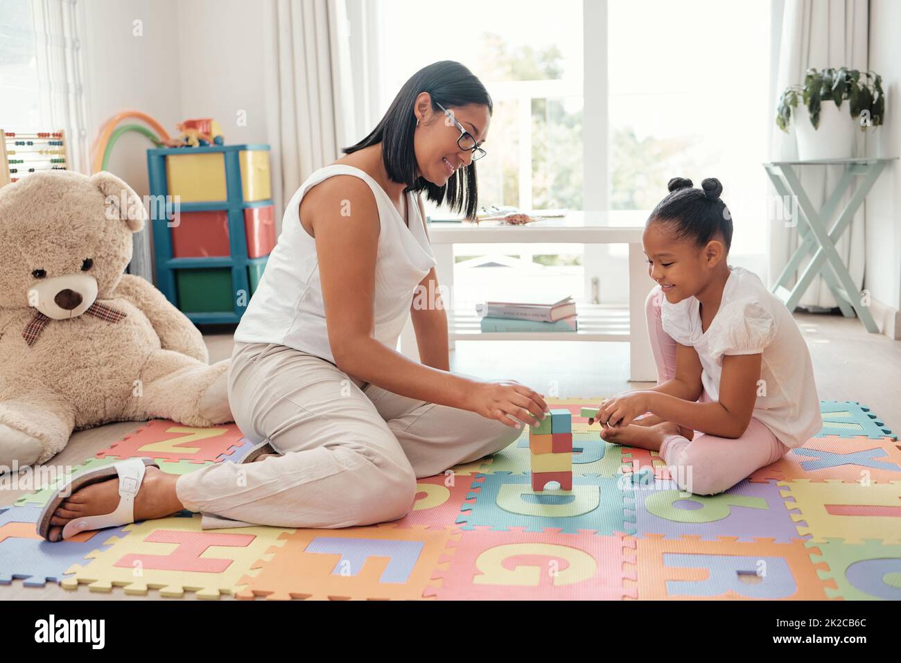 Teaching Spiel, Gebäude Spielzeug und Mutter mit Mädchen im Kinderzimmer für Wachstum, Wissen und Problemlösung. Mama, Kind oder schwarze Menschen zusammen auf einem Stockfoto