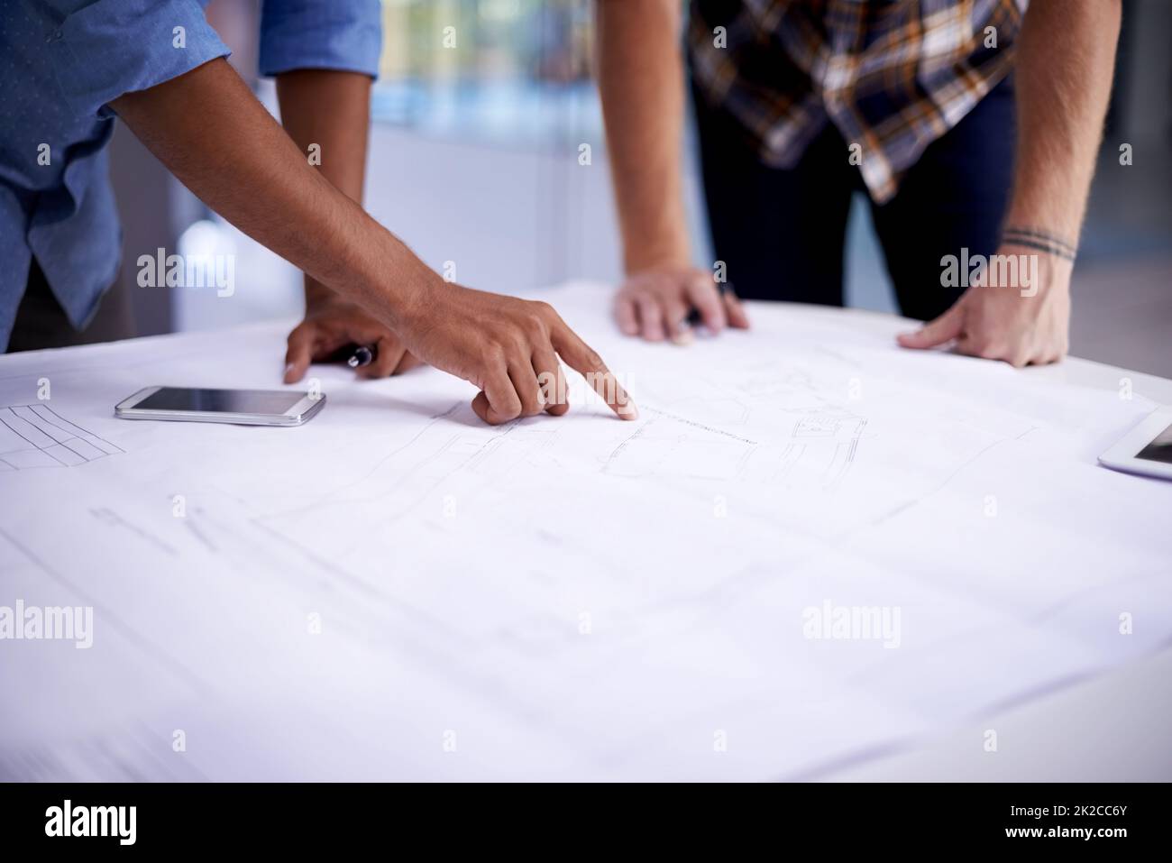 Gemeinsam großartige Dinge schaffen. Nahaufnahme von zwei jungen Architekten, die in einem Büro an Blaupausen arbeiten. Stockfoto