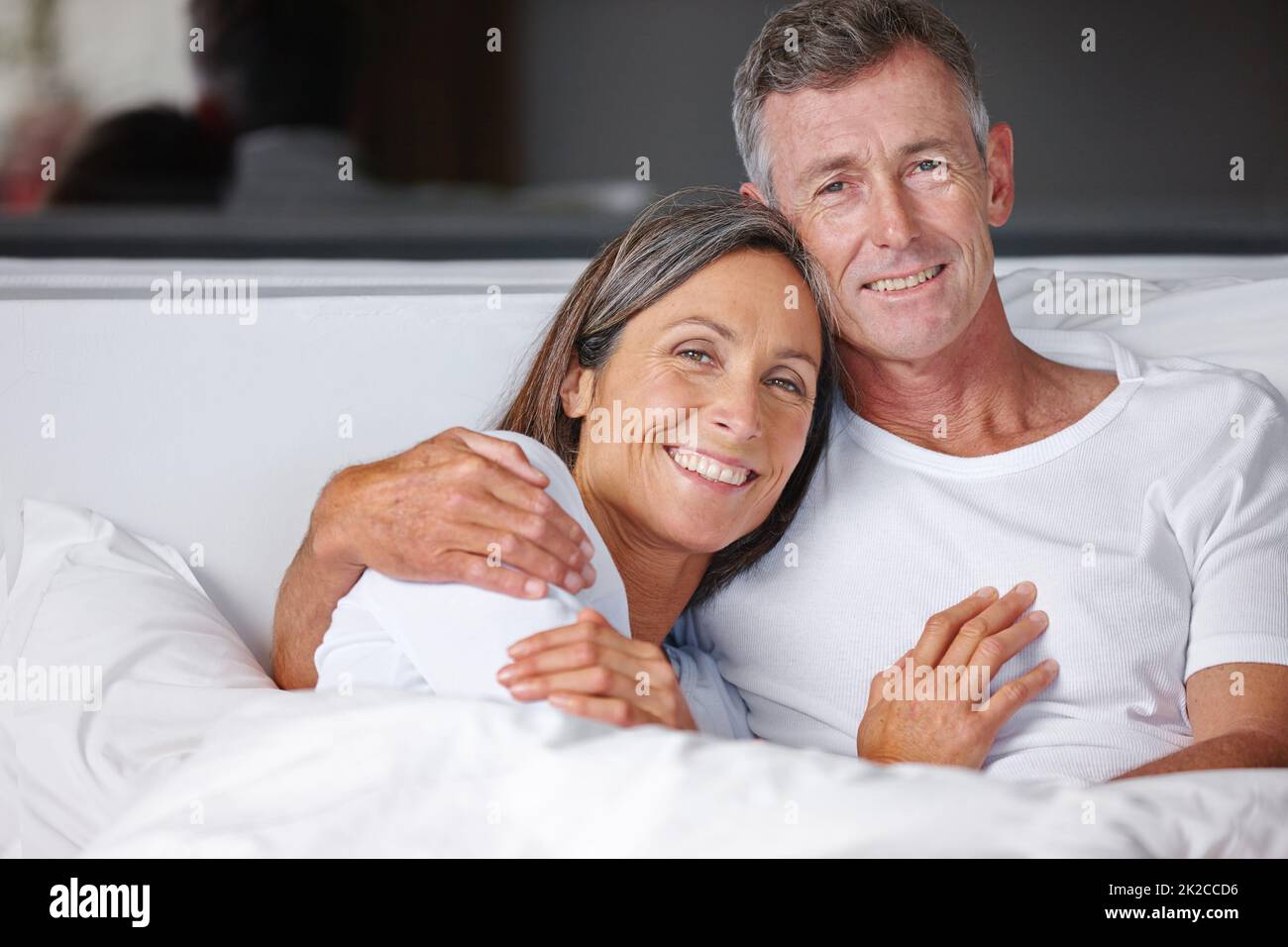 Zeit für ein paar Kuscheln. Porträt eines liebevollen reifen Paares, das im Bett kuschelt. Stockfoto