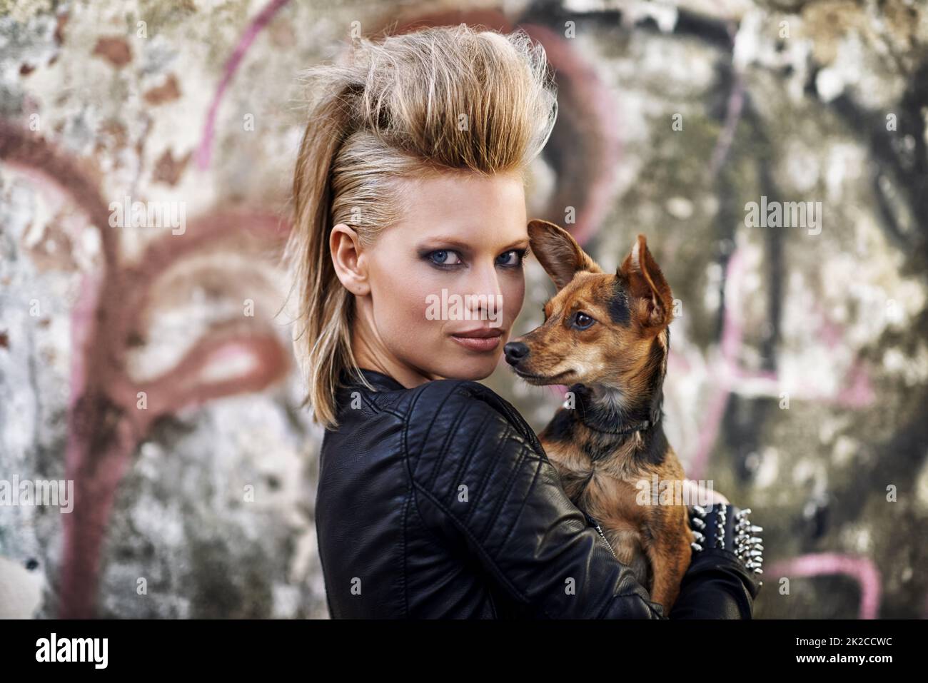 Urbane Hunde. Eine junge trendige Frau mit einem kleinen Hund in einer städtischen Umgebung. Stockfoto