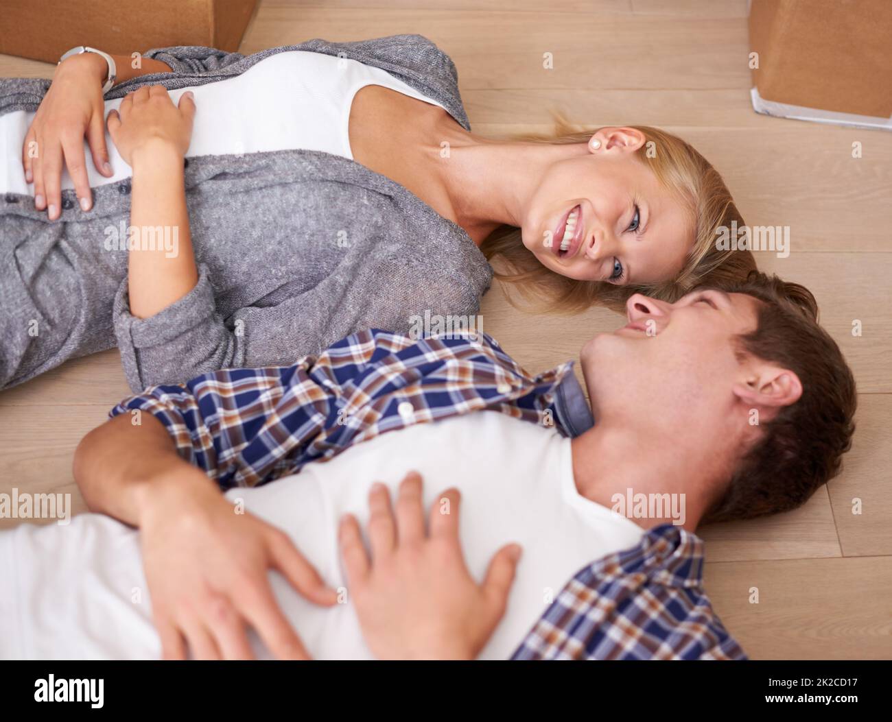 Der Umzug macht mich müde. Aufnahme eines Paares, das nach einem langen Tag voller Umzug glücklich auf dem Boden lag. Stockfoto