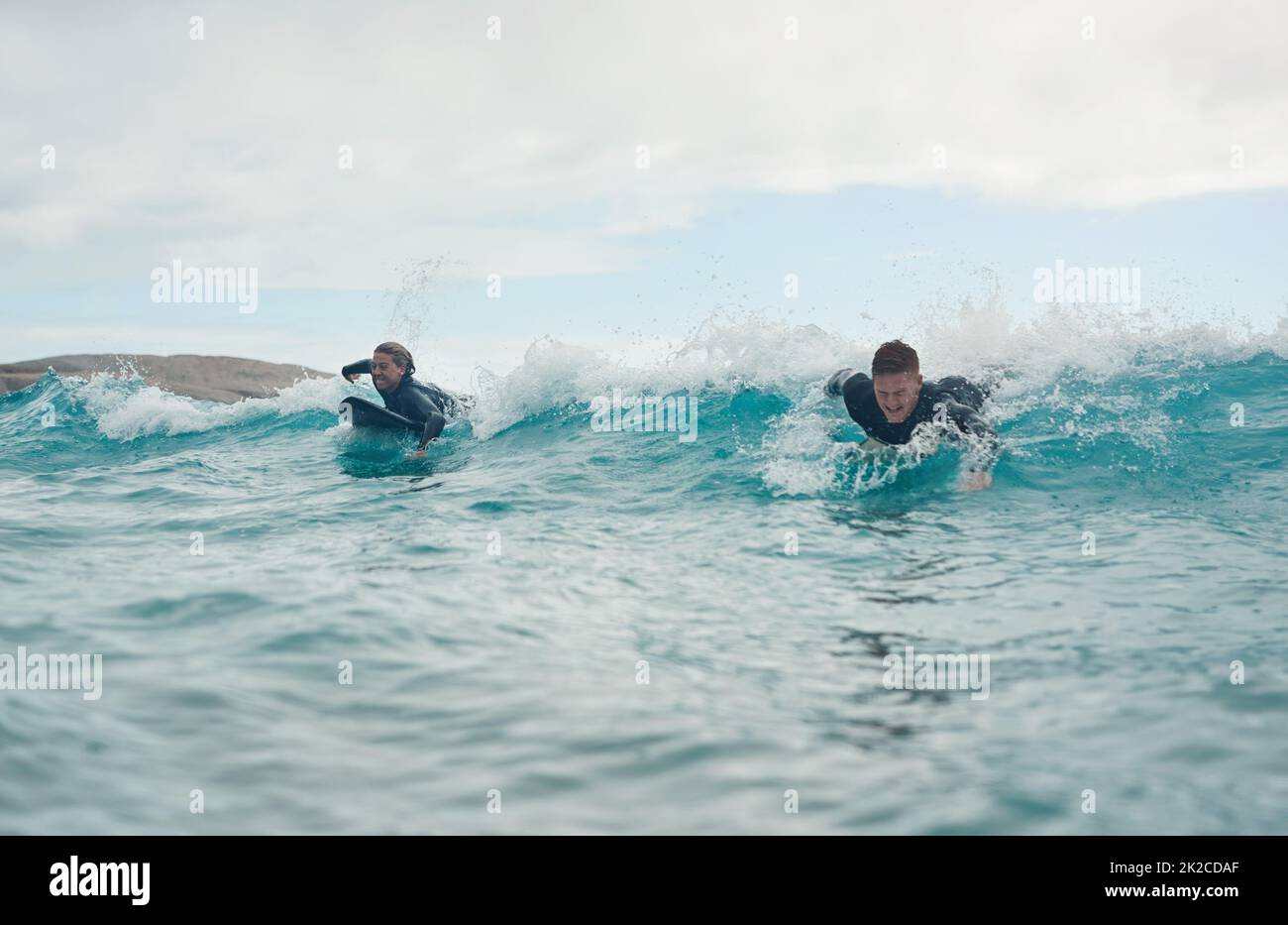 Surfen lässt uns eins mit der Natur fühlen. Aufnahme eines jungen Paares, das gemeinsam am Strand surft. Stockfoto