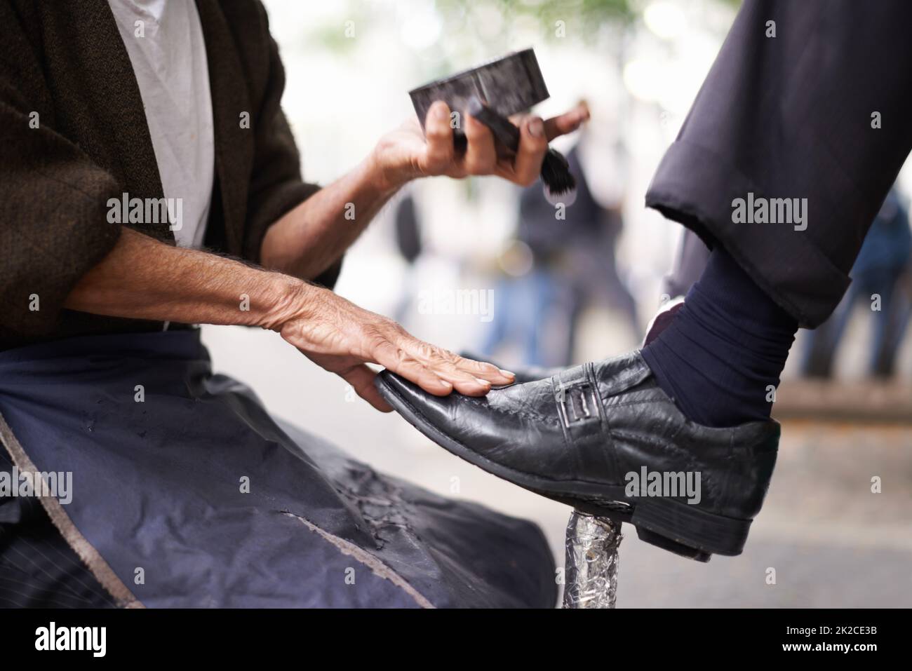 Damit die Schuhe der Geschäftsmänner glänzte. Kurzer Schuss eines Schuhlers, der die Schuhe eines Geschäftsmanns glänzt. Stockfoto