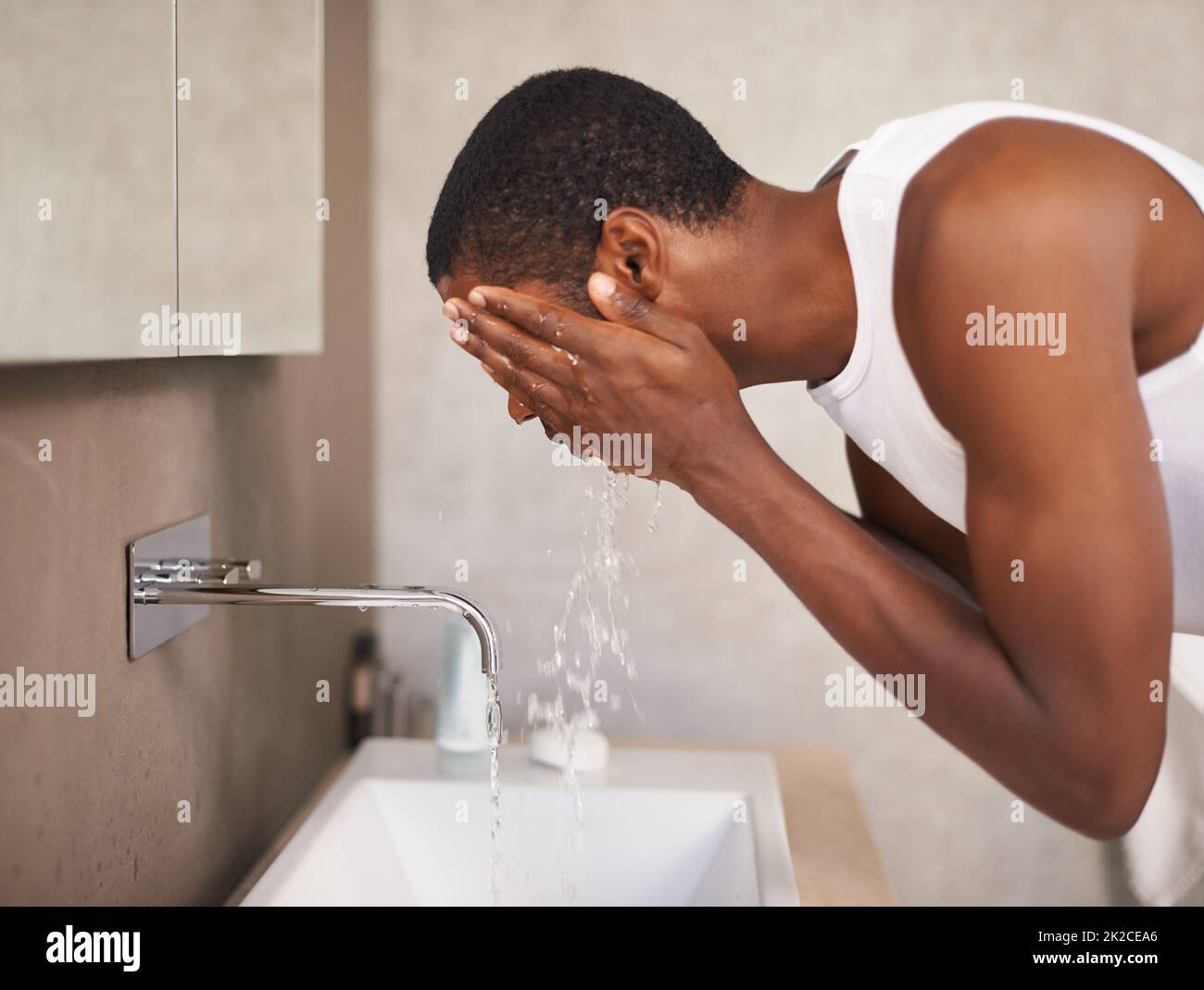 Sauber halten für die Damen. Ein junger Mann wascht sich das Gesicht. Stockfoto