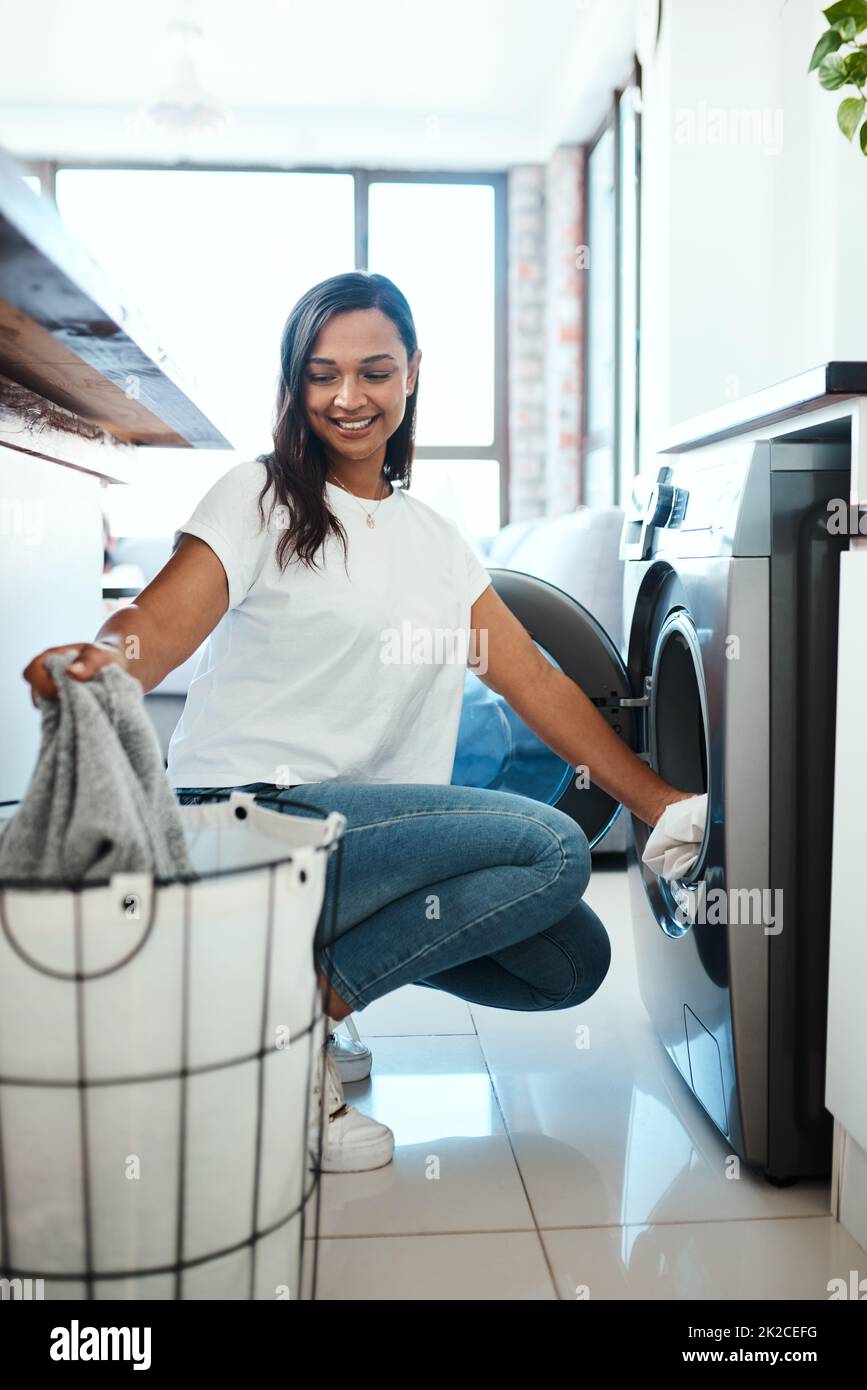 Wäsche waschen, bevor sie sich stapelt. Aufnahme einer jungen Frau, die zu Hause eine Waschmaschine benutzt. Stockfoto