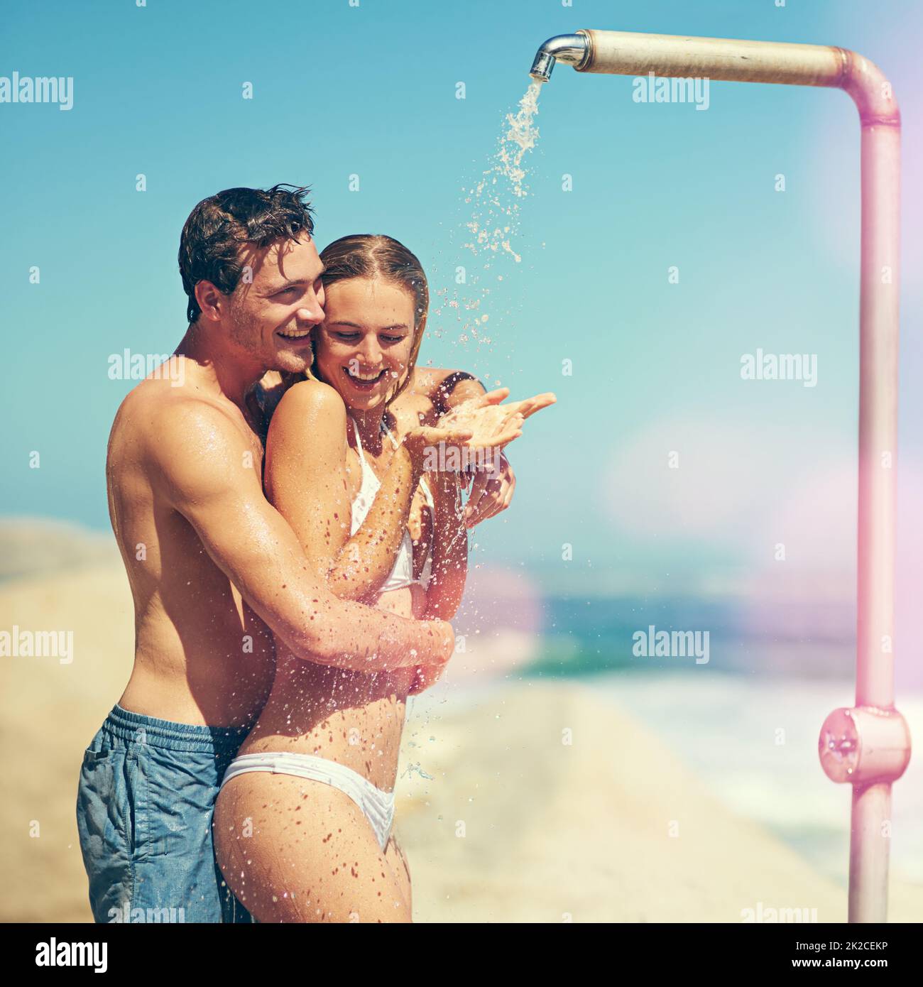 Du sollst mich waschen. Kurzer Schuss eines liebevollen jungen Paares, das am Strand duscht. Stockfoto