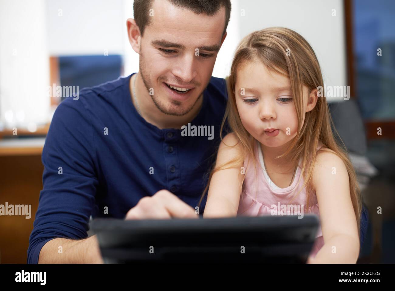 Lassen Sie sich von Papa zeigen, wie man das macht. Vater und Tochter verbinden sich über Technologie. Stockfoto
