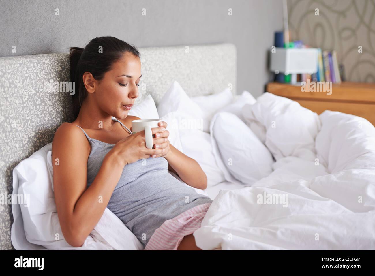 Einfach unvergleichlich... eine Tasse Kaffee am Morgen. Attraktive junge Frau bläst den heißen Dampf aus ihrem Morgenkaffee. Stockfoto