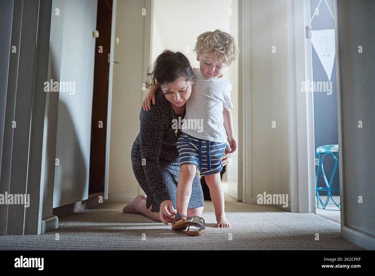 Machen Sie sich bereit für den Spaß vor Ihnen. Aufnahme einer Mutter, die ihrem Sohn hilft, seine Schuhe zu Hause anzuziehen. Stockfoto