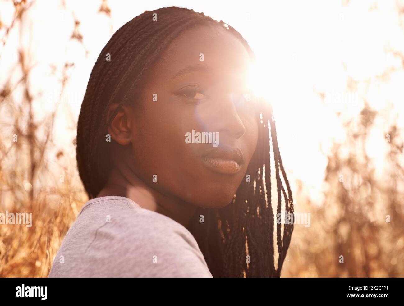 Die goldene Stunde. Porträt eines attraktiven Teenagers auf einem Feld mit der Sonne hinter sich. Stockfoto