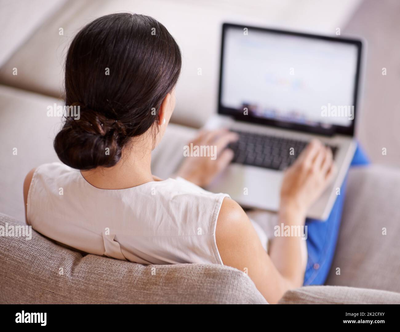 Etwas Zeit zum Surfen einnimmen. Über die Schulter einer jungen Frau, die mit einem Laptop auf einem Sofa sitzt. Stockfoto