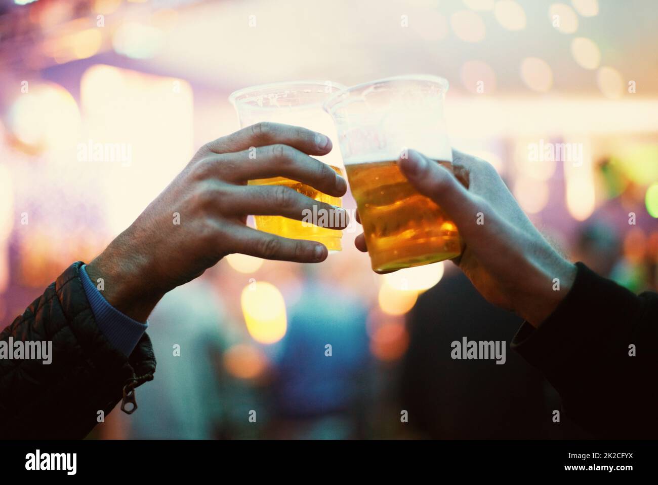 Erinnerung an den Moment. Zwei Freunde toasten zu den guten Zeiten mit Plastikbechern Bier - Musikfestival. Stockfoto