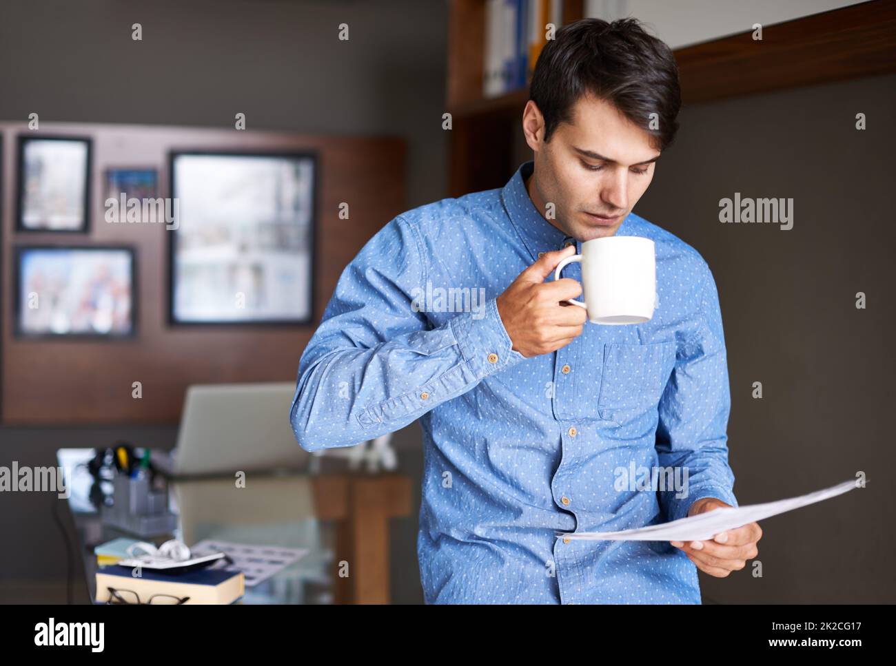 Kaffeekonzentration. Ein junger Geschäftsmann trinkt Kaffee, während er einige Papiere durchläuft. Stockfoto