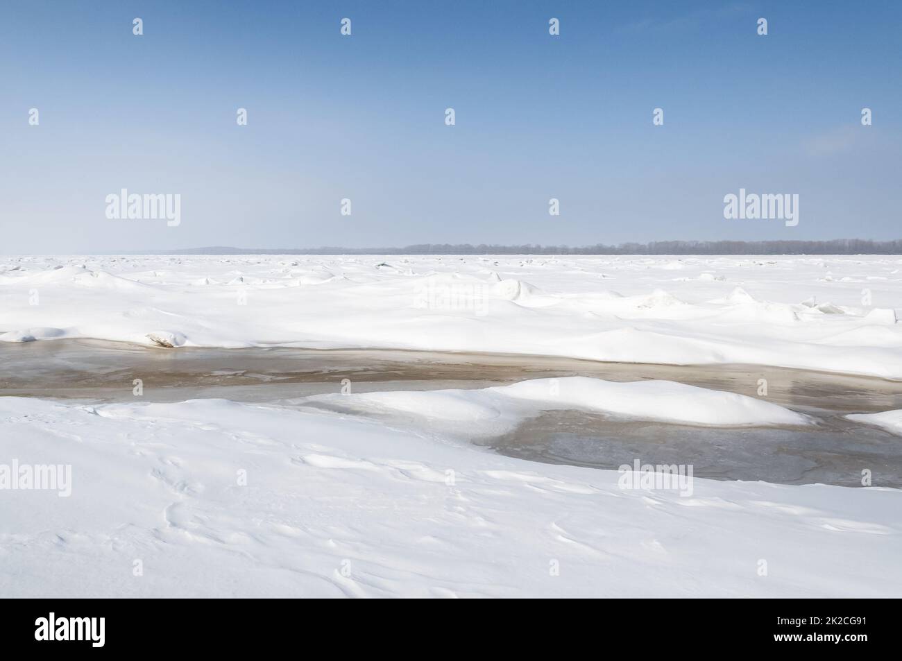 Atemberaubender Blick auf den gefrorenen Fluss bedeckt mit Eisstücken und weißem Frostschnee. Verschneite Wüste. Stockfoto