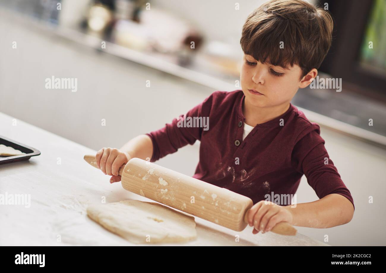 Hes ein natürlich geborener Bäcker. Aufnahme eines Jungen, der in der Küche Teig rollt. Stockfoto