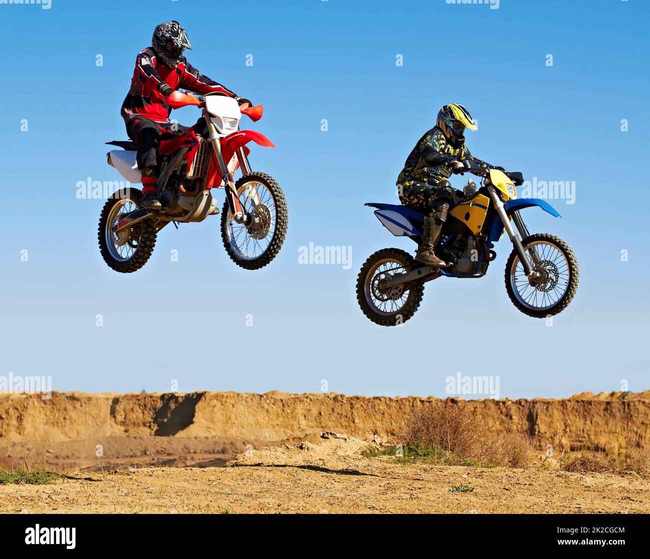 Im Gleichklang springen. Action-Aufnahme von zwei Dirt Bikern mitten in der Luft. Stockfoto