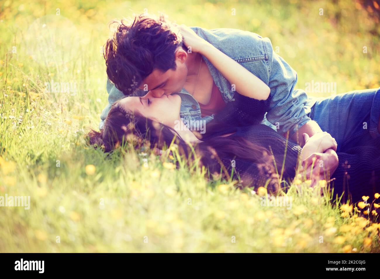 Jugendliche Romantik. Bild im Vintage-Stil eines jungen Paares, das sich in einem Sommerfeld romantisch küsst. Stockfoto