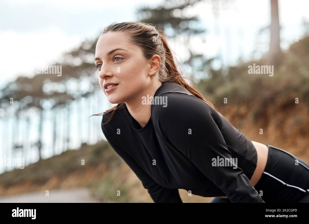 Ich nehme mir einen Moment Zeit, um zu atmen. Eine kurze Aufnahme einer attraktiven jungen Frau, die sich nach ihrem morgendlichen Lauf im Freien einen Moment zur Ruhe nimmt. Stockfoto