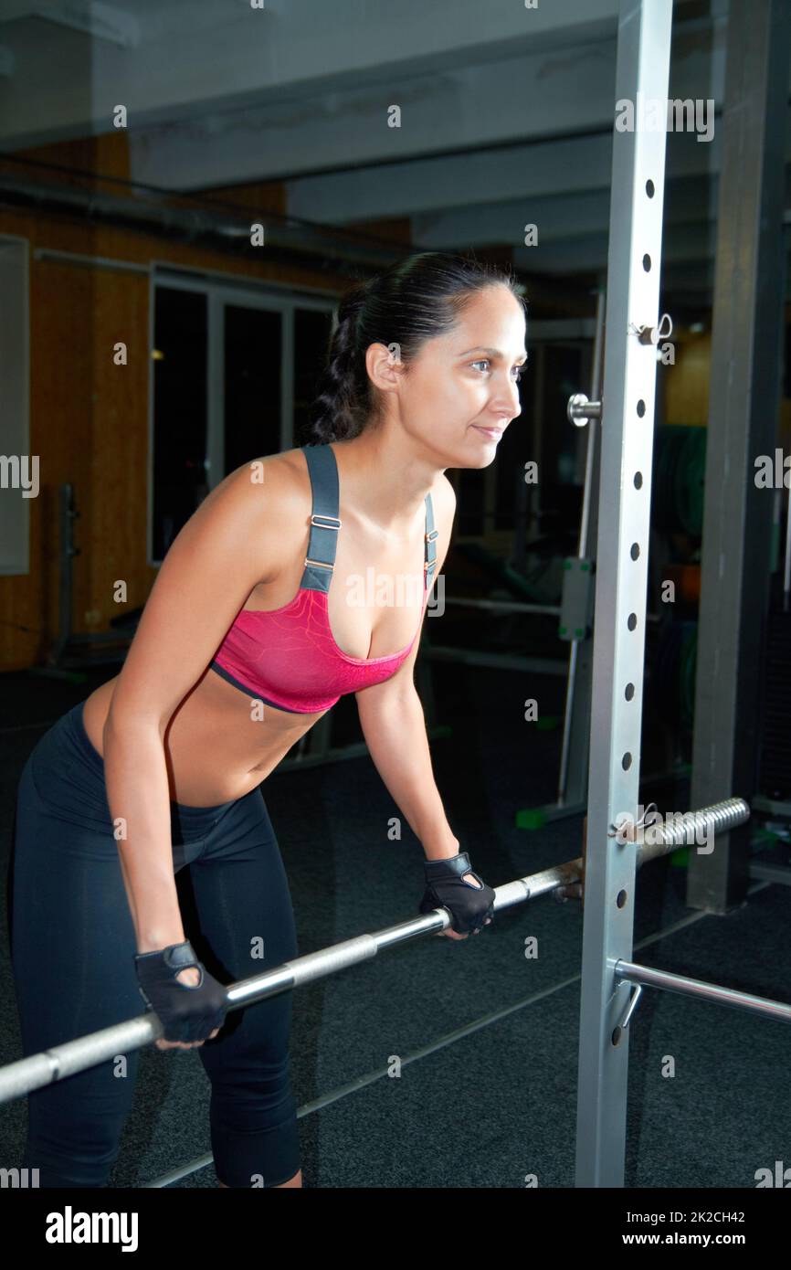 Ihren Körper formt. Aufnahme einer attraktiven jungen Frau, die im Fitnessstudio Eisen pumpt. Stockfoto