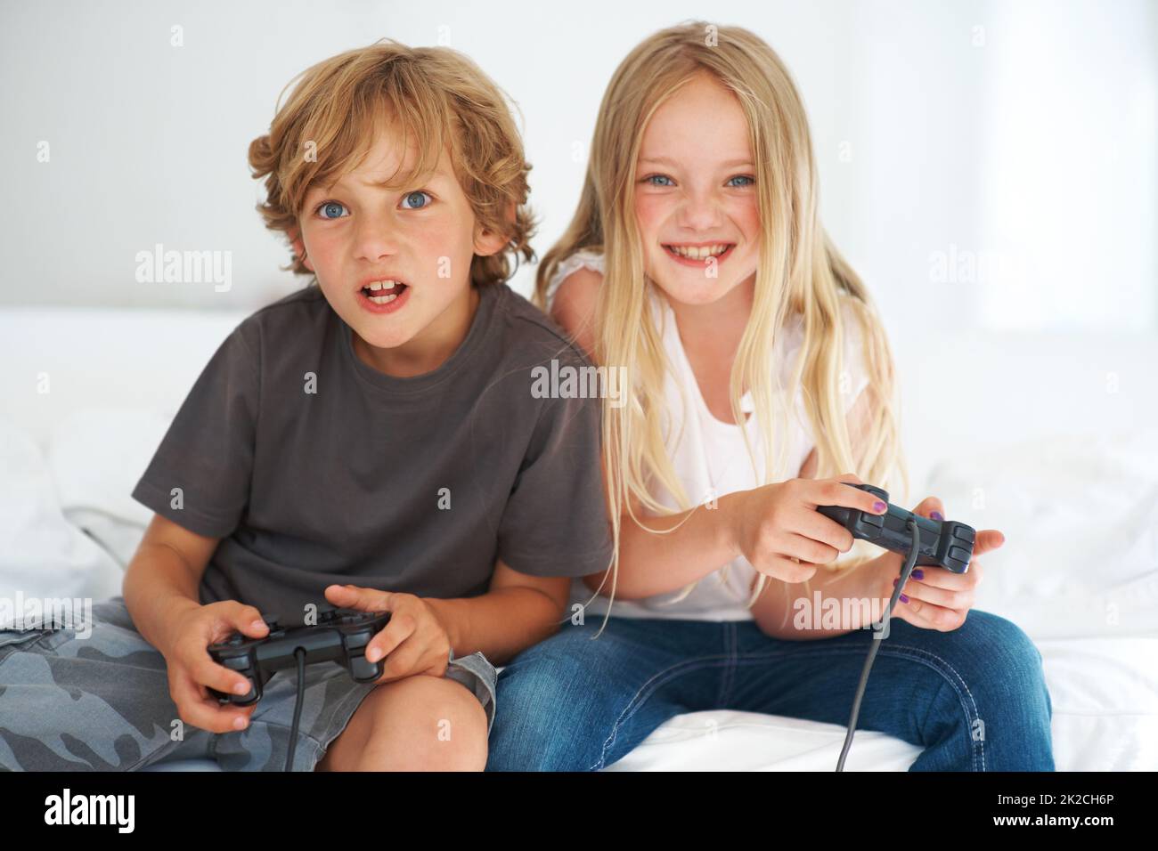 Geschwisterbindung. Junge Geschwister sitzen auf dem Sofa und spielen ein Videospiel. Stockfoto