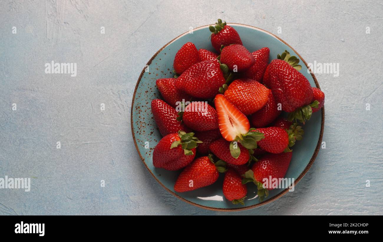 Erdbeere frische Bio-Früchte auf einem Teller. Erdbeeren mit Blättern. Isoliert auf grauem Hintergrund. Stockfoto