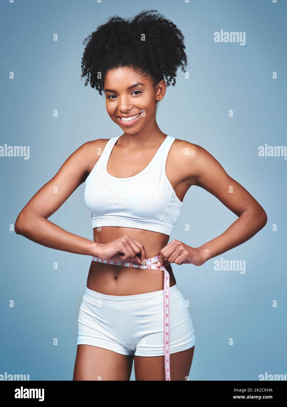 Ich verliere mehr, als ich verhandeln konnte. Aufnahme einer attraktiven jungen Frau, die ihre Taille vor einem grauen Hintergrund misst. Stockfoto