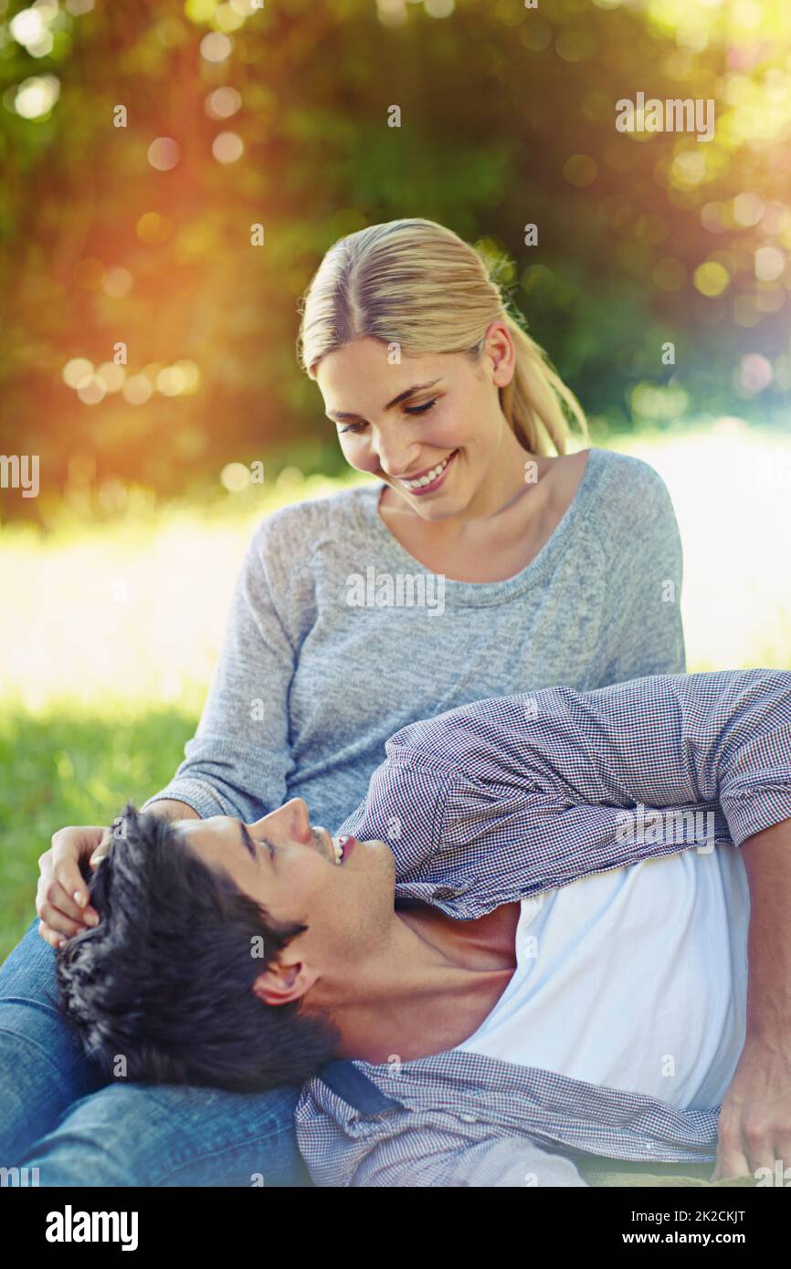 Die Liebe fiel ihr einfach in den Schoß. Aufnahme eines glücklichen jungen Paares, das auf dem Gras liegt und einen liebevollen Moment miteinander teilt. Stockfoto