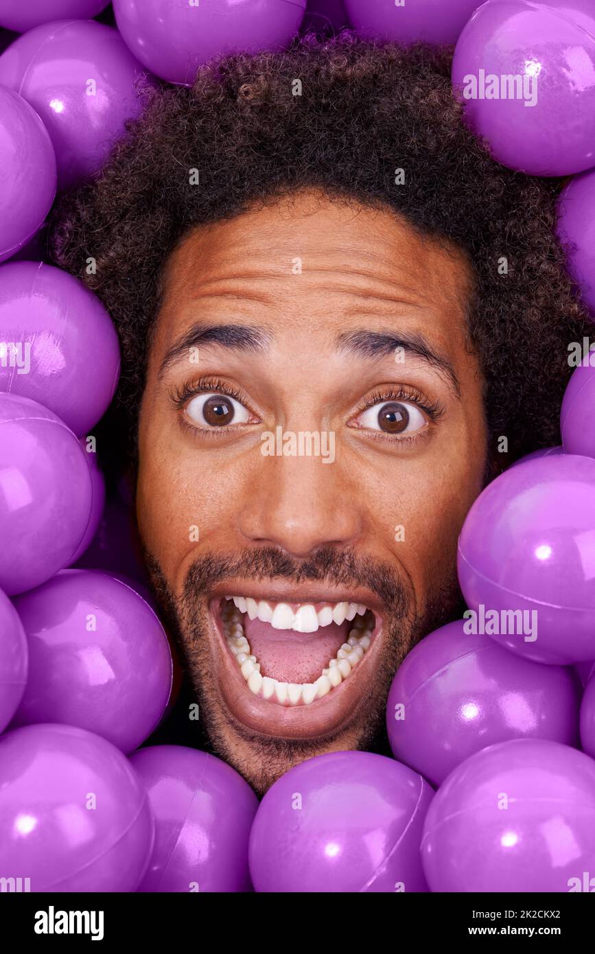 Hey, dieser Ballkasten ist verrückt. Ein junges Gesicht von Schwarzen unter purpurnen Boxenbällen. Stockfoto