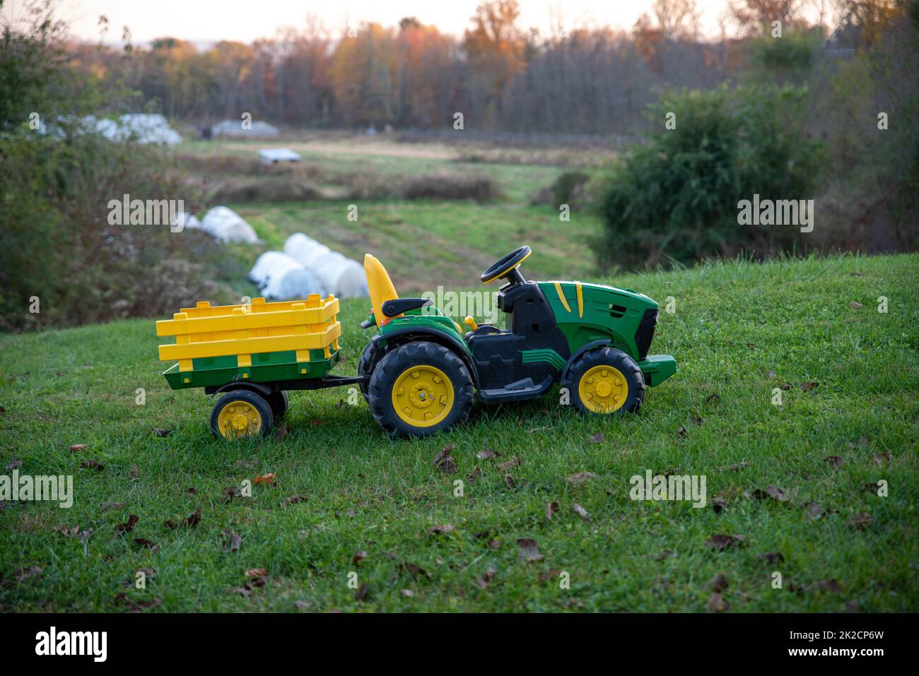 Kinderspielzeug-Reittraktor im grünen Grashof mit Farm-Hintergrund Stockfoto