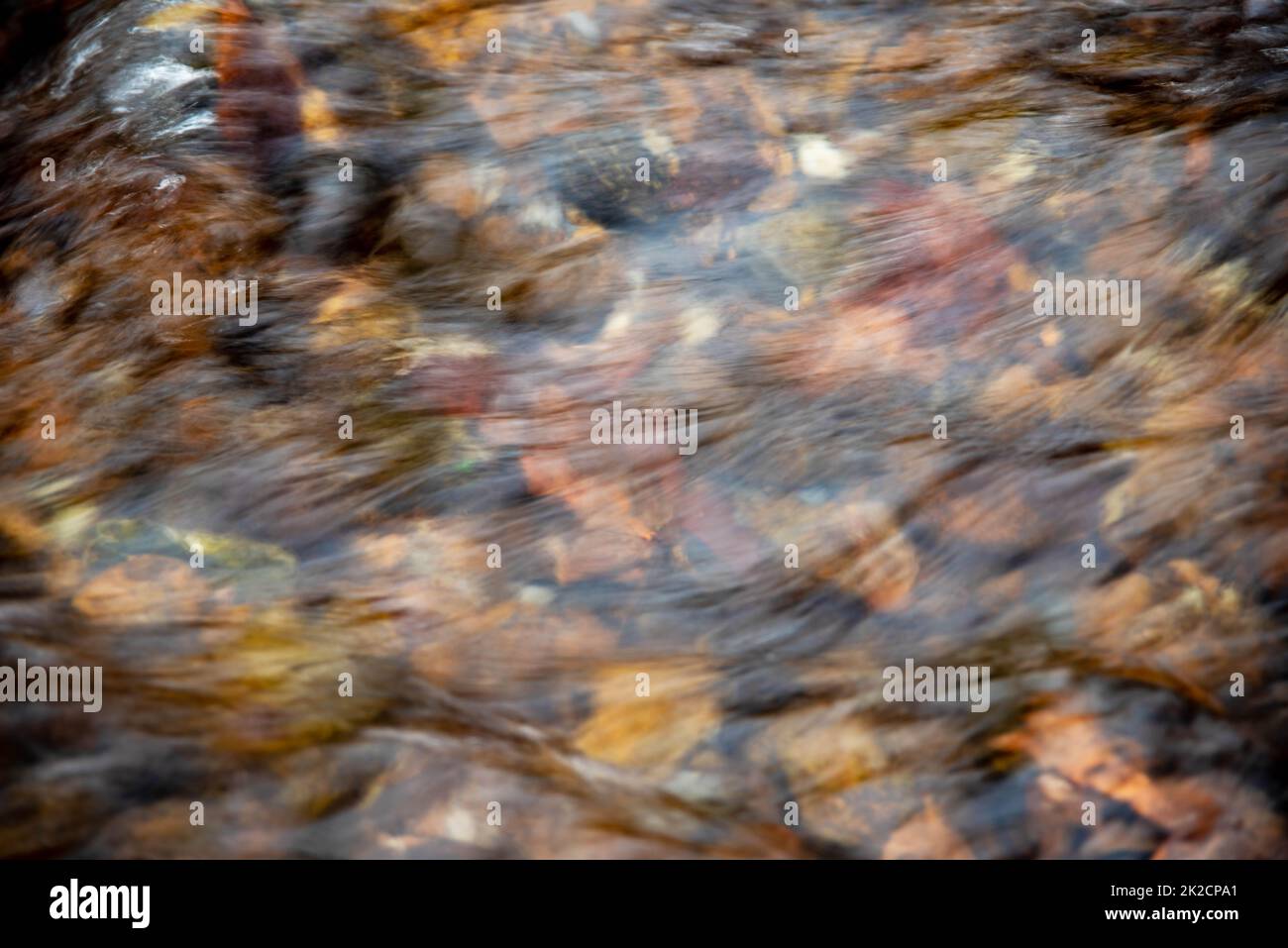 Blick aus einem großen Winkel auf den flachen Fluss über farbenfrohe Steine Stockfoto