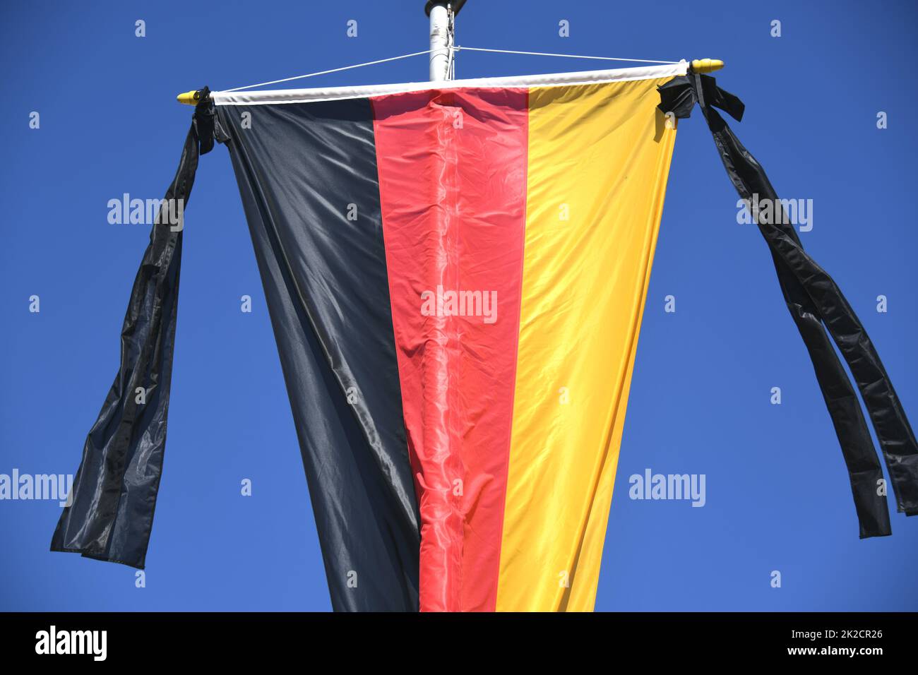 Die Nationalflagge der Bundesrepublik Deutschland, schwarz, rot und golden, hängt an der Fahnenstange. Als Symbol der nationalen Trauer ist das Trauerband mit zwei schwarzen Bändern an der Flagge befestigt. Stockfoto