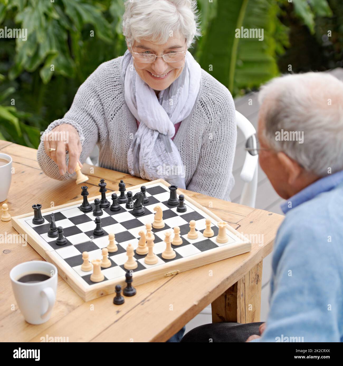 Diese nächsten Schritte werden mir das Spiel gewinnen. Ein älteres Paar spielt im Freien zusammen Schach. Stockfoto