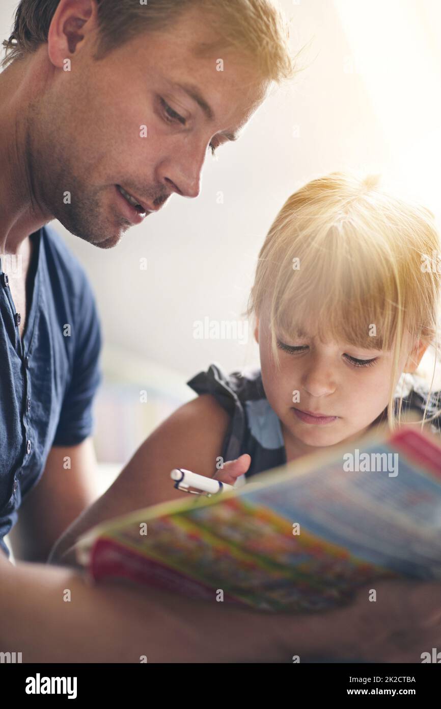 Seiner Tochter gewidmet. Aufnahme eines alleinerziehenden Vaters, der seiner Tochter bei ihren Hausaufgaben hilft. Stockfoto