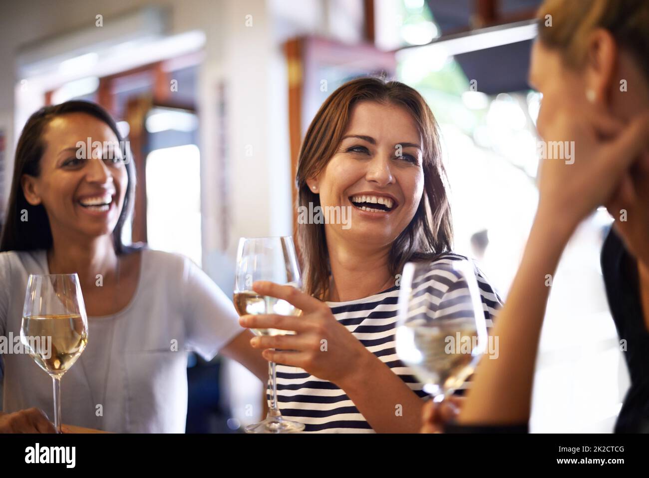 Die Mädchen feiern mit einem Glas Wein. Eine kurze Aufnahme von drei Frauen, die ein Glas Weißwein genießen. Stockfoto