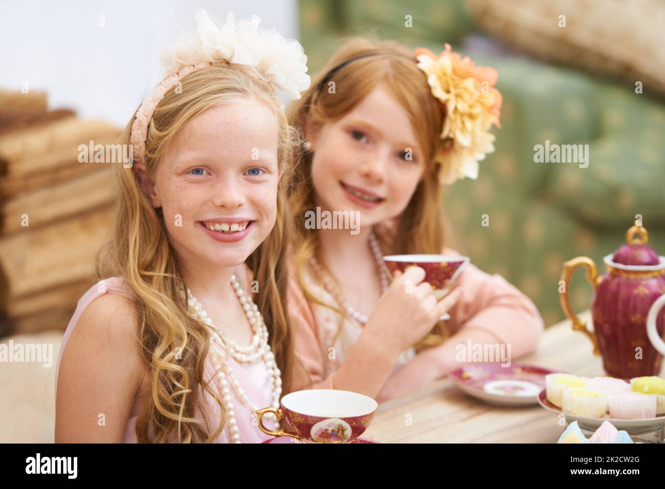 Die Teestunde. Zwei Freunde kleiden sich und feiern draußen im Garten eine Teeparty. Stockfoto